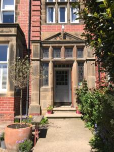 ein altes Backsteingebäude mit einer Tür und Blumen in der Unterkunft Fernleigh in Robin Hood's Bay