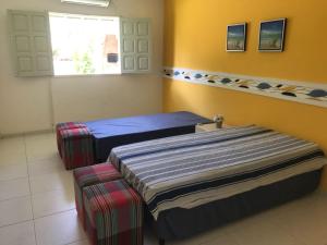 a room with two beds and a window at Serrambi - 4 quartos com piscina e churrasqueira in Porto De Galinhas