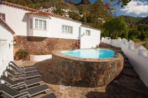 a swimming pool with a stone wall next to a house at Casa Rural La Asomadita in Agaete