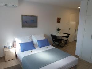 ein Schlafzimmer mit einem Bett mit blauen Kissen und einem Tisch in der Unterkunft Villa Big Blue, Tisno in Tisno