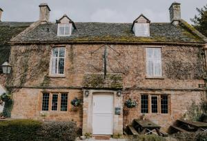 una vieja casa de ladrillo con una puerta blanca en The Falkland Arms, en Chipping Norton