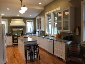 a kitchen with white cabinets and a large island with bar stools at Robert Porter House Inn in Victoria