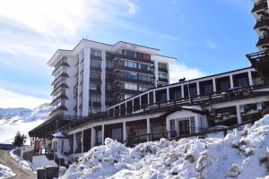 um grande edifício com neve empilhada à sua frente em El Colorado Ski depto In Out 2 ambientes em Farellones