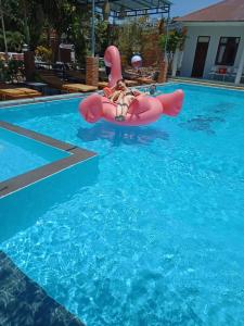 a woman riding on a pink raft in a swimming pool at Song Huong Hotel Mui Ne in Mui Ne