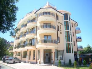a tall white building with a car parked in front of it at Family Hotel Golden Lion in Primorsko