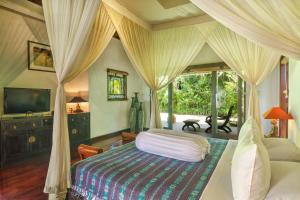 a bedroom with a canopy bed and a television at Villa Plawa Asri in Seminyak +55 photos