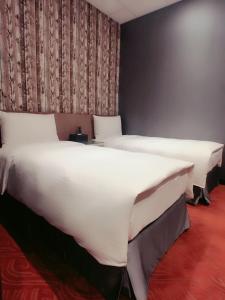 two beds in a room with white sheets at 耘荷居 Yún Inn in Taipei