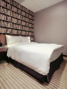 a large white bed in a room with a wall of books at 耘荷居 Yún Inn in Taipei
