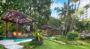 a playground in a park with trees and a building at The Bayview Beach Resort in Batu Ferringhi
