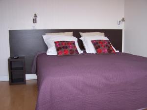 een slaapkamer met een paars bed met kussens bij Logis Hôtel Le Jabron in La Bégude-de-Mazenc