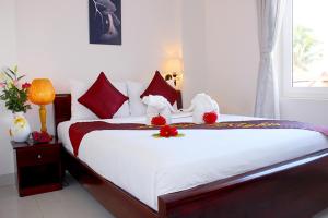 a bedroom with a large white bed with red pillows at 1001 Nights Hotel in Mui Ne