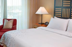 a hotel room with a bed and a red chair at World Golf Village Renaissance St. Augustine Resort in St. Augustine