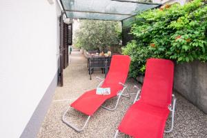 two red chairs and a table on a patio at Apartments Stasic in Vrbnik