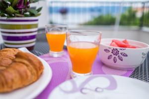 a table with two glasses of orange juice and a bowl of fruit at Apartments Stasic in Vrbnik