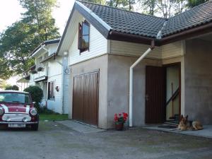 a dog laying in front of a house with a car at Merekalda Accommodation - Adults Only in Käsmu