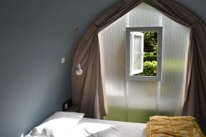 a bedroom with a bed and a window at Camping des Drouilhèdes in Peyremale