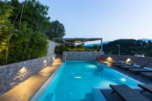 a swimming pool with lounge chairs next to a stone wall at Elea Villas - Aspro & Blanche in Almirida