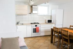 a kitchen with white cabinets and a table and a stove at Amber Studio Apartment Alpine Retreat Soča Valley in Kobarid