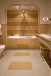 a bathroom with a tub and a toilet and a sink at Grand Hotel Savoia in Genoa