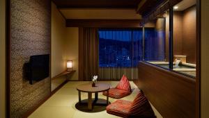 a hotel room with a table and chairs and a window at Laforet Ito Onsen Yunoniwa in Ito