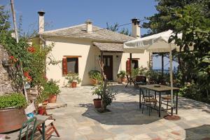 un patio con mesa y sillas frente a una casa en Guesthouse Kleopatra's, en Tsagkarada