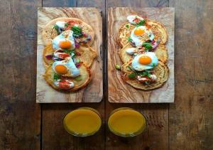 two pizzas with eggs on top on a wooden table at Argo in Listvyanka