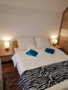 a white bed with two blue pillows on it at Apartmani F&A in Zlatibor