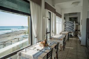 a restaurant with tables and a view of the beach at Hotel Maremola in Pietra Ligure