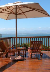 a patio with two chairs and an umbrella on a deck at Aquamarine Guest House in Mossel Bay