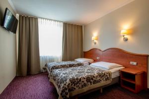 a hotel room with two beds and a window at Hotel Krakus in Kraków