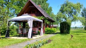 una casa con sedie e ombrellone in cortile di Wiśniowy Sad a Białowieża