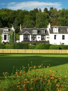 a large white house with a green yard with flowers at Buchan Guest House in Moffat