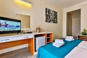 a room with two beds and a tv on a desk at Hotel Magnolija in Budva
