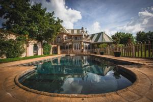 a swimming pool in front of a house with a fence at Schoon Huis Manor in Kempton Park