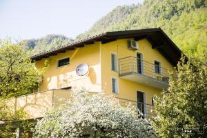 a yellow house with a balcony and trees at Emerald Soca Apartment in Tolmin