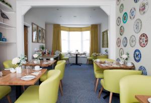 a restaurant with wooden tables and yellow chairs at Sea Spray Hotel in Brighton & Hove