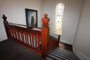 a wooden staircase with a stained glass window on the wall at Ballarat Premier Apartments in Ballarat