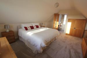 een slaapkamer met een groot wit bed met rode kussens bij Glenside Cottage with Hot Tub in Solva