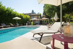 una piscina con sillas y sombrillas junto a una piscina en Logis Hotel Le Petit Casset, en La Boisse