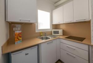 a small kitchen with white cabinets and a sink at Apartamentos AR Muntanya Mar in Blanes