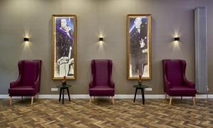 a waiting room with purple chairs and pictures on the wall at Hollywood Media Hotel am Kurfürstendamm in Berlin