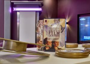 a book on a table with a pile of gold plates at Hollywood Media Hotel am Kurfürstendamm in Berlin