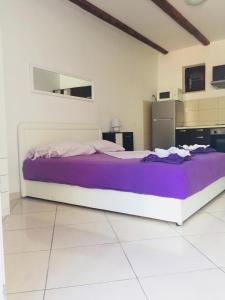 een groot bed in een witte kamer met paarse lakens bij Apartments Paula in Korčula