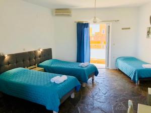 a room with three beds with blue sheets at Delta Studios in Gerani