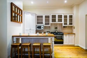 a kitchen with white cabinets and a wooden island with stools at Okiep Country Hotel in OʼOkiep