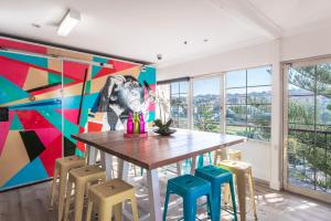 a dining room with a table and chairs and a mural at Mad Monkey Coogee Beach in Sydney