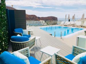 een zwembad met blauwe stoelen en tafels op een terras bij Calypso Boutique Apartments in Puerto Rico de Gran Canaria