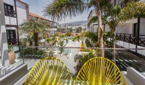 a balcony with yellow chairs and a view of a pool at Vanilla Garden Boutique Hotel - Adults Only in Playa de las Americas