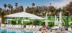 a group of people sitting around a pool with umbrellas at Vanilla Garden Boutique Hotel - Adults Only in Playa de las Americas