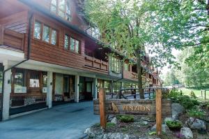 a wooden building with a sign in front of it at Penzión Teniscentrum in Tatranská Lomnica